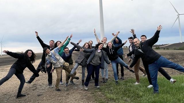 Group photo of students posing near a wind turbine